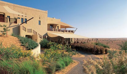 Al Maha Desert Resort and Spa Dubai exterior stone building in the desert with fabric awnings
