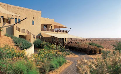 Al Maha Desert Resort and Spa Dubai exterior stone building in the desert with fabric awnings