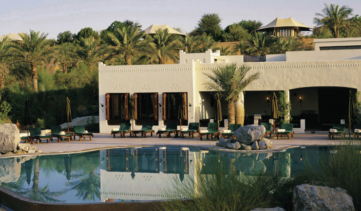 Al Maha Desert Resort and Spa Dubai outdoor pool with loungers and white buildings