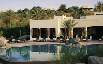 Al Maha Desert Resort and Spa Dubai outdoor pool with loungers and white buildings