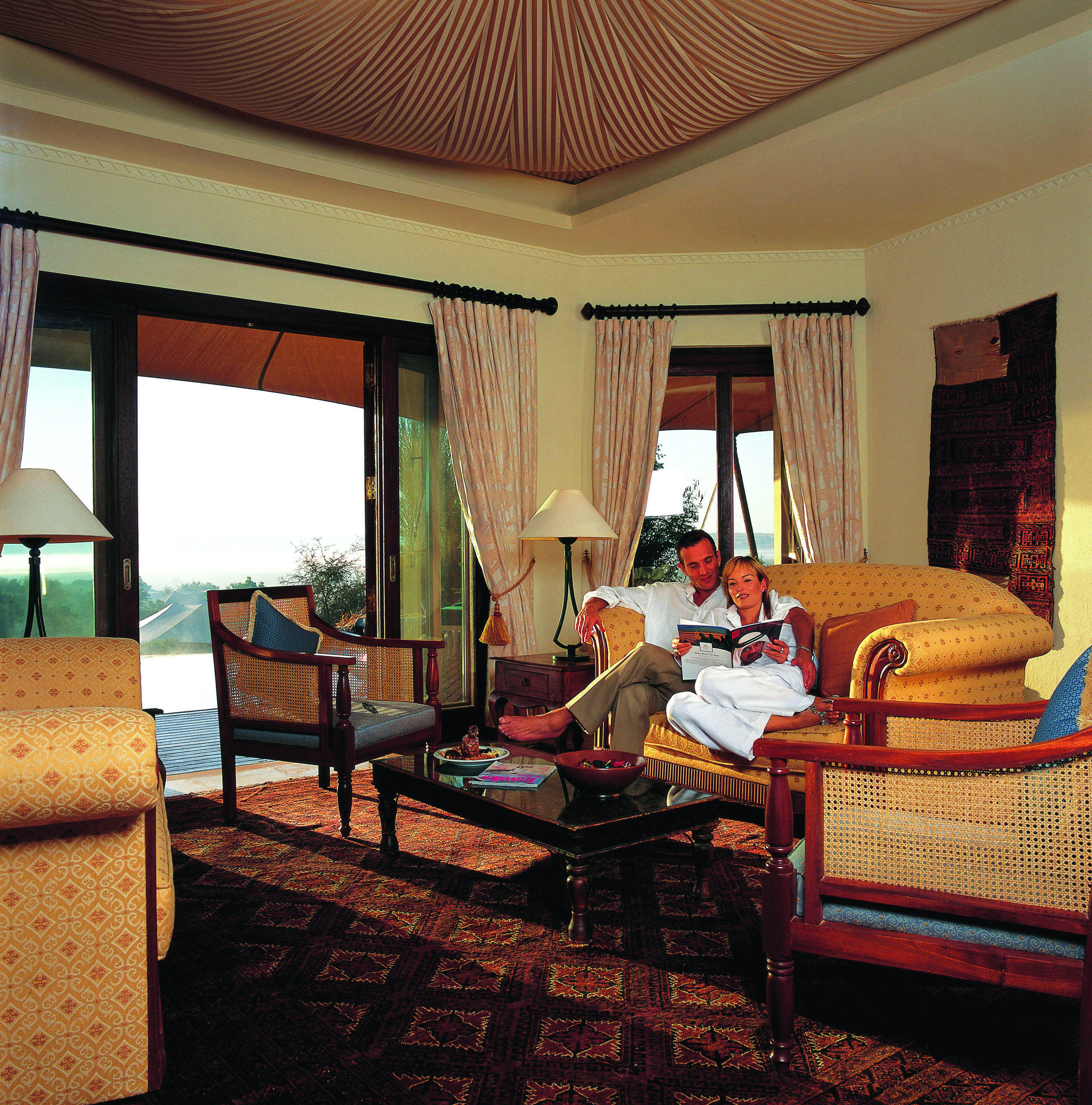 Al Maha Desert Resort and Spa Dubai suite lounge with sofa and armchairs with patio access