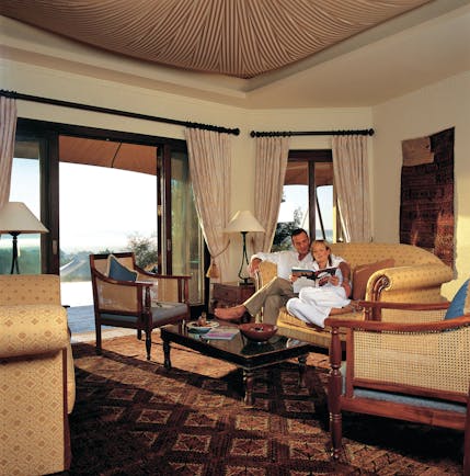 Al Maha Desert Resort and Spa Dubai suite lounge with sofa and armchairs with patio access