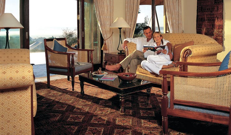 Al Maha Desert Resort and Spa Dubai suite lounge with sofa and armchairs with patio access