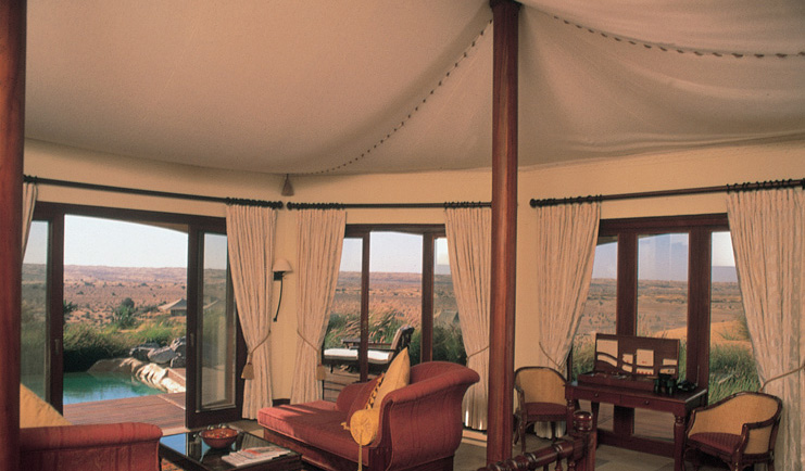 Al Maha Desert Resort and Spa Dubai suite tented suite sitting room with sofas and view of pool