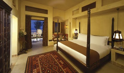 Bab Al Shams Desert Resort and Spa Dubai bedroom with corner sofa and access to patio 