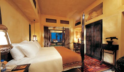 Bab Al Shams Desert Resort and Spa Dubai bedroom with carved furniture and access to terrace 