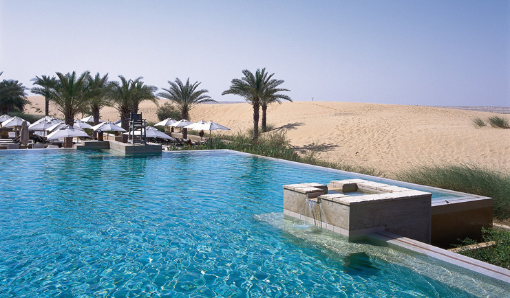 Bab Al Shams Desert Resort and Spa Dubai desert pool with umbrellas and palm trees