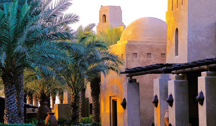 Bab Al Shams Desert Resort and Spa Dubai exterior architecture stone building with domed roof and palm trees