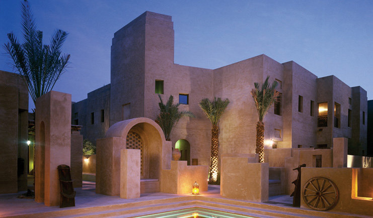 Bab Al Shams Desert Resort and Spa Dubai exterior night stone architecture with pool and wheel