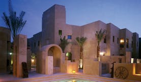 Bab Al Shams Desert Resort and Spa Dubai exterior night stone architecture with pool and wheel
