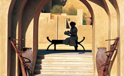 Bab Al Shams Desert Resort and Spa Dubai terrace woman reading a book in a courtyard