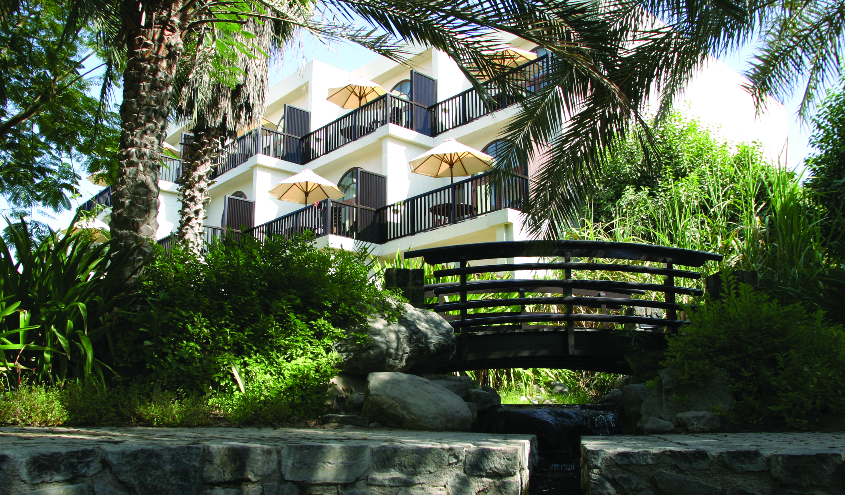 Palm Tree Court Jebel Ali Dubai exterior building with balconies overlooking garden with bridge