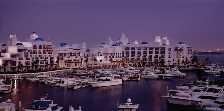 Exterior of hotel with purple sky and the marina in front with boats 