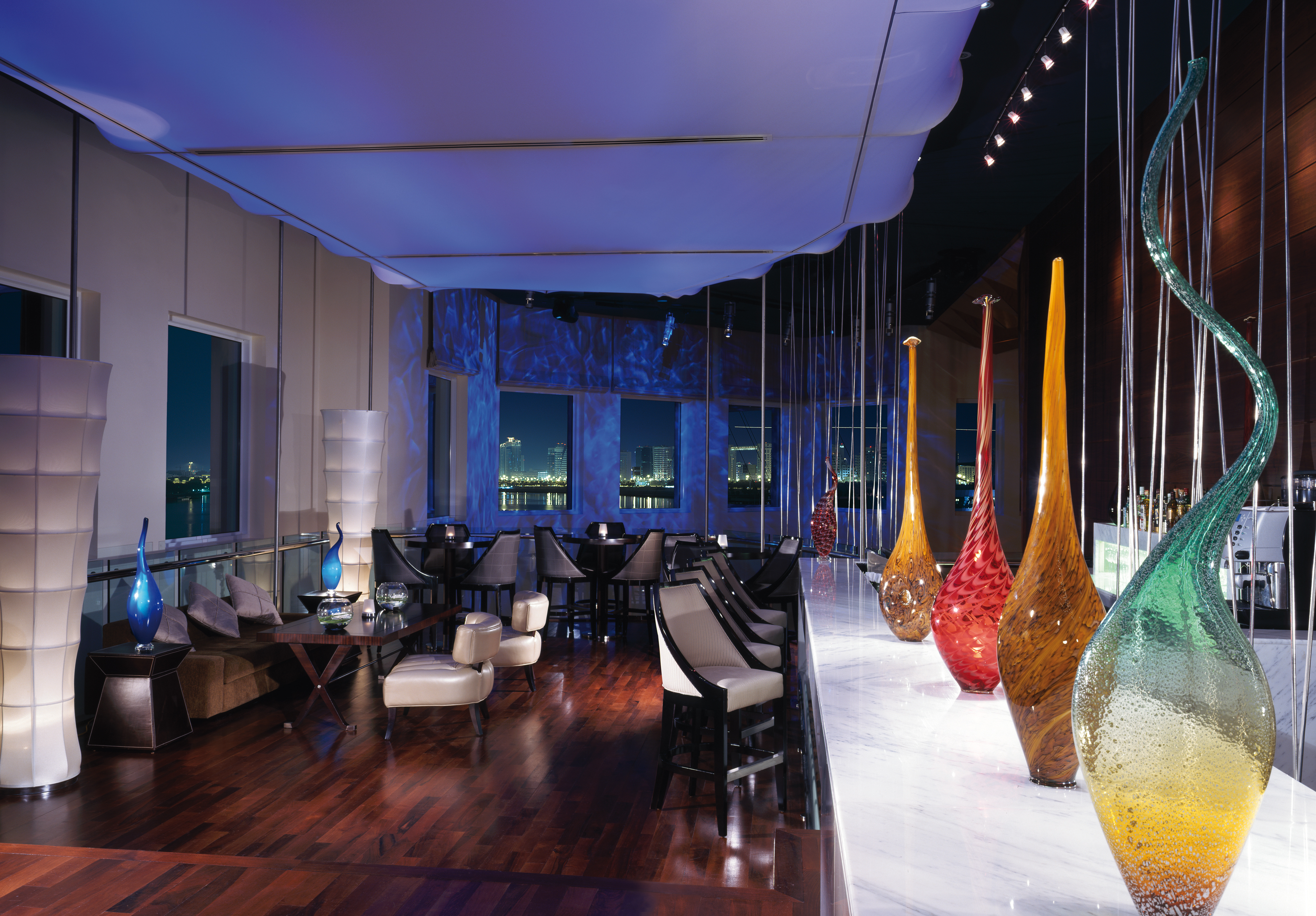 Restaurant with tables and chairs set out and coloured vases for decoration 