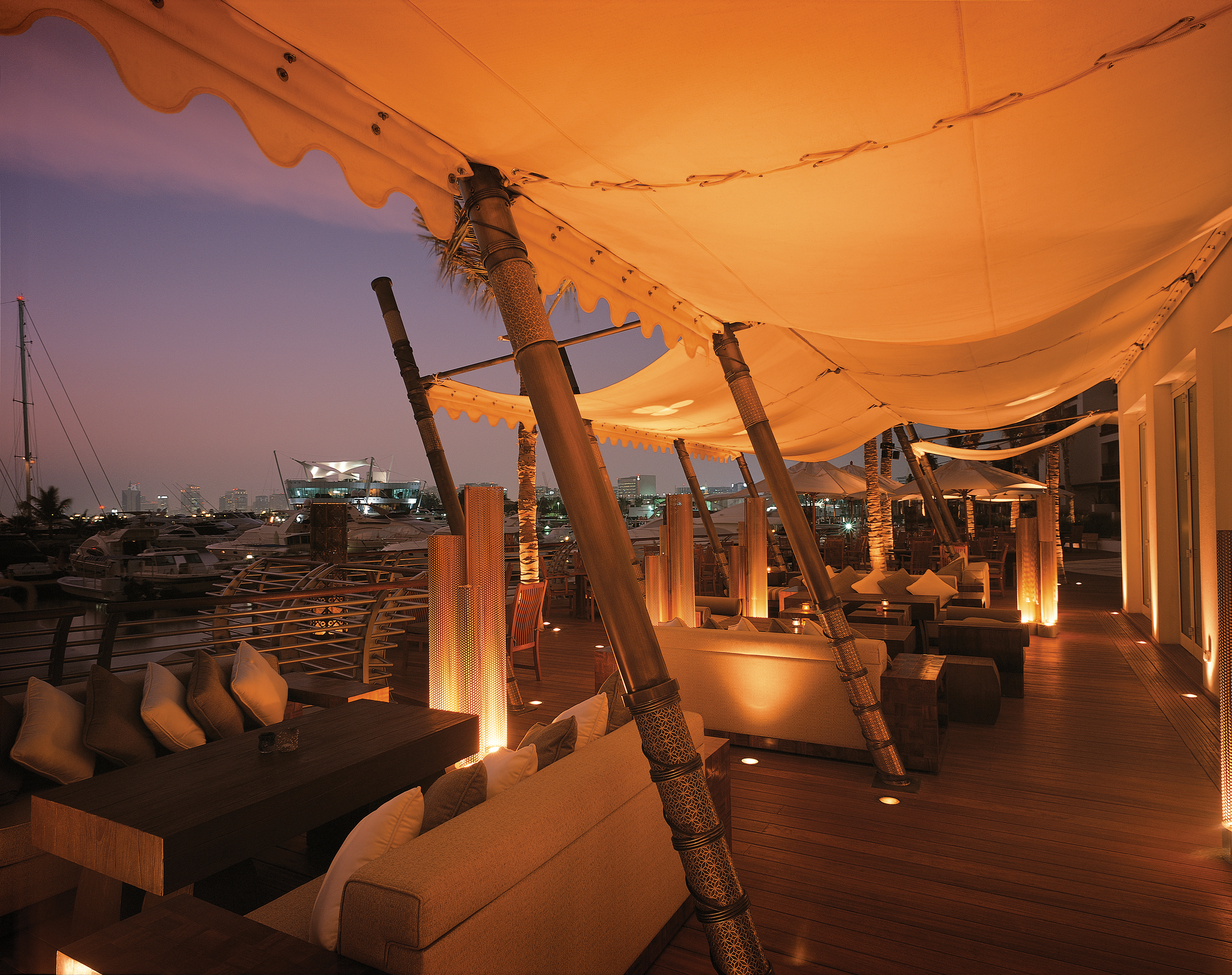 Terrace at night with wood pannelled floors and cushioned seats 