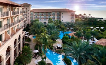 The Ritz-Carlton Dubai exterior view of hotel with balconies pools and palm trees