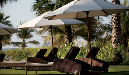 The Ritz-Carlton Dubai garden loungers sun loungers and umbrellas in gardens with palms