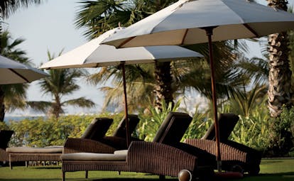 The Ritz-Carlton Dubai garden loungers sun loungers and umbrellas in gardens with palms