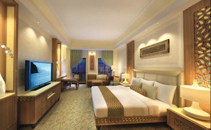 Al Bustan Palace Hotel Oman bedroom with television sofa and balcony
