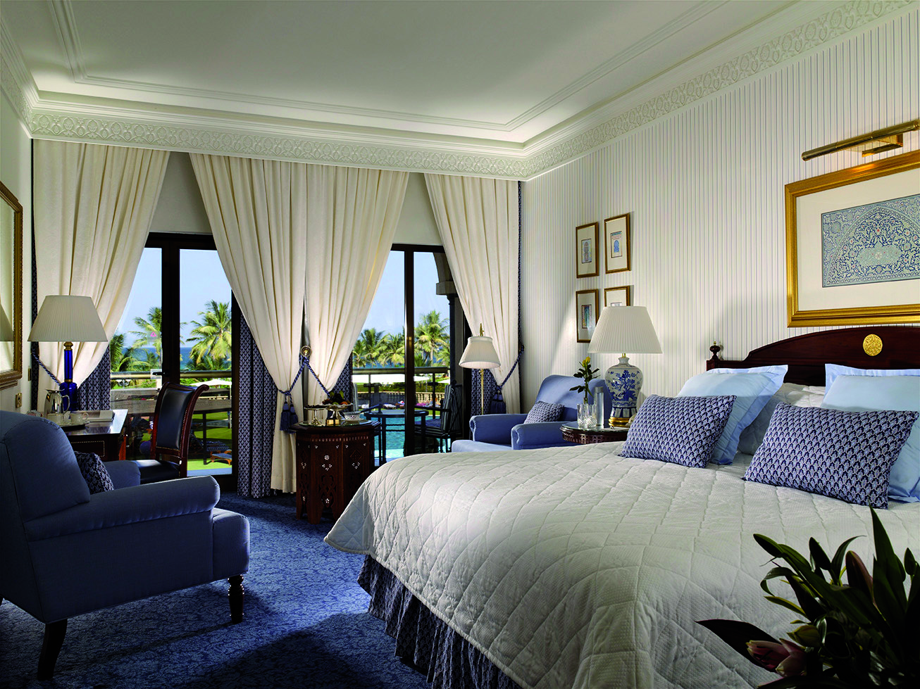 Al Bustan Palace Hotel Oman deluxe bedroom with sofa armchair and balcony