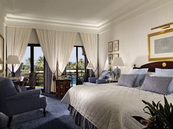 Al Bustan Palace Hotel Oman deluxe bedroom with sofa armchair and balcony