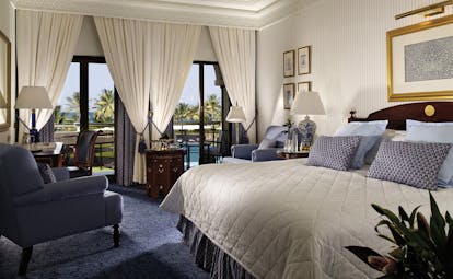 Al Bustan Palace Hotel Oman deluxe bedroom with sofa armchair and balcony