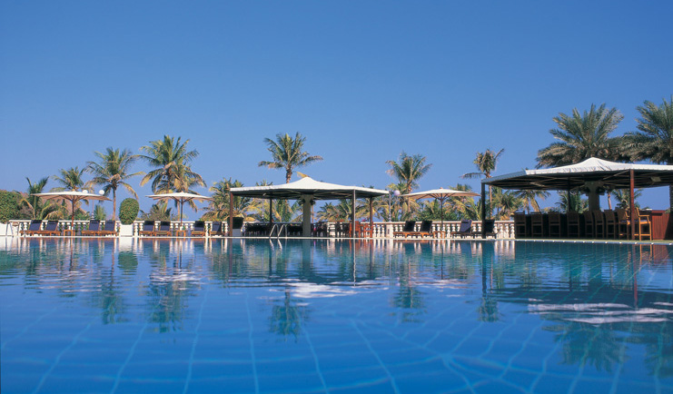 Al Bustan Palace Hotel Oman swimming pool with white umbrellas and loungers