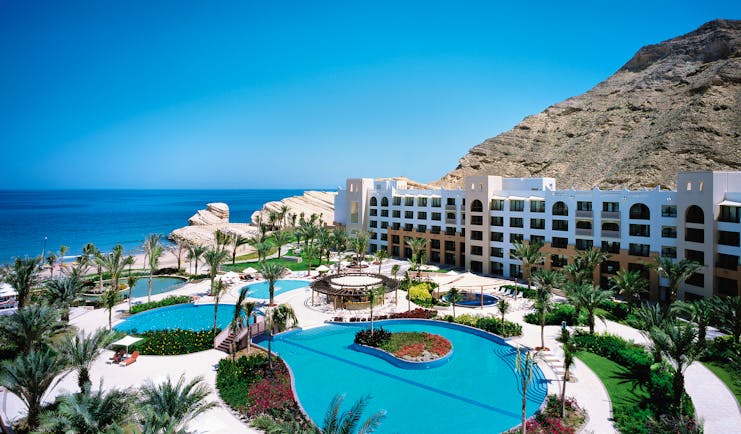 View of hotel and pool with white hotel building, blue pool with sea in distance