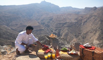 Six Senses Zighy Bay Oman mountain picnic waiter setting up a picnic in the mountains