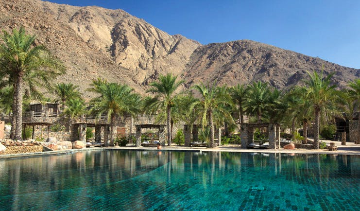 Six Senses Zighy Bay Oman outdoor pool overlooked by mountains with covered loungers