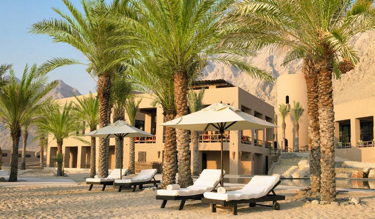 Six Senses Zighy Bay Oman private beach with loungers umbrellas and palm trees