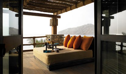 Six Senses Zighy Bay Oman retreat terrace lounge bed on balcony with drink and view of sea and mountain