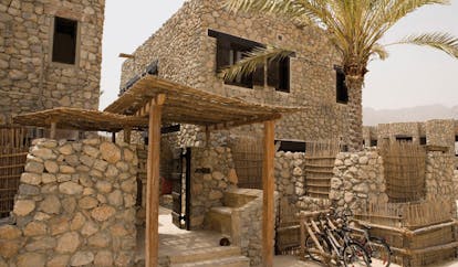 Six Senses Zighy Bay Oman villa exterior stone buildings with balconies and bicycles