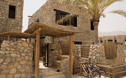 Six Senses Zighy Bay Oman villa exterior stone buildings with balconies and bicycles