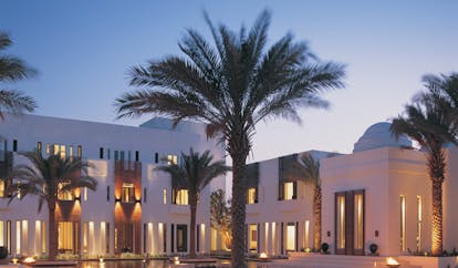 The Chedi Muscat Oman courtyard surrounded by white buildings and palm trees