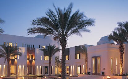 The Chedi Muscat Oman courtyard surrounded by white buildings and palm trees