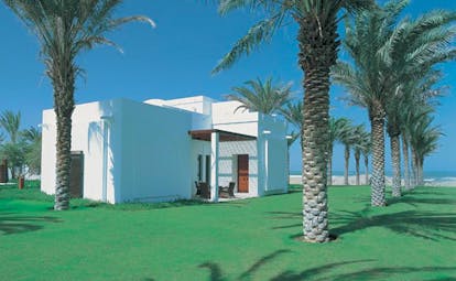 The Chedi Muscat Oman exterior white building with flat roof and palm trees