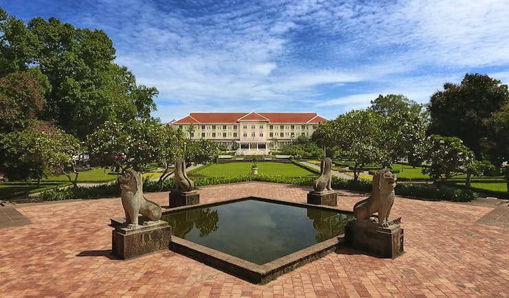Raffles D'Angkor exterior, hotel building, grand architecture, patio with ornate water feature, lawns, trees