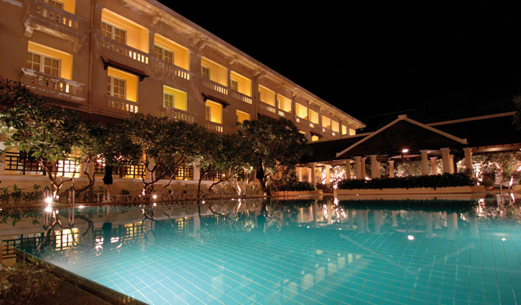 Raffles Hotel Le Royal Cambodia exterior night swimming pool trees romantic lighting