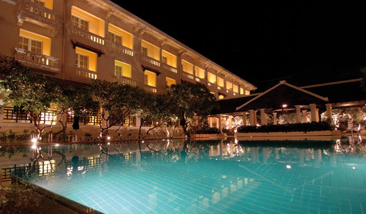 Raffles Hotel Le Royal Cambodia exterior night swimming pool trees romantic lighting