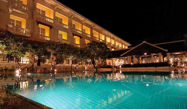 Raffles Hotel Le Royal Cambodia exterior night swimming pool trees romantic lighting