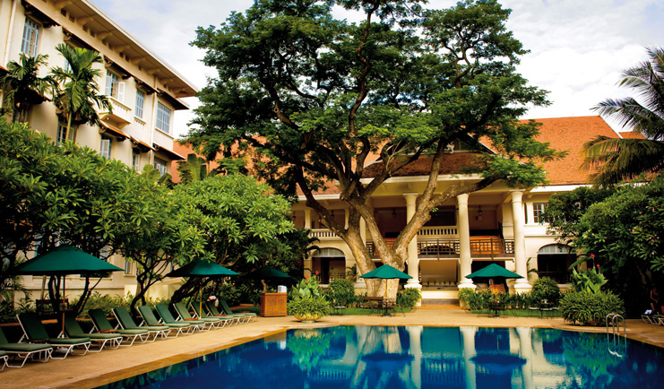 Raffles Hotel Le Royal Cambodia exterior pool loungers trees hotel building