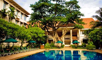 Raffles Hotel Le Royal Cambodia exterior pool loungers trees hotel building