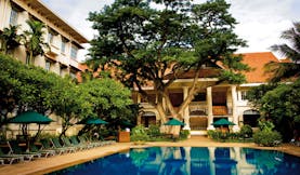 Raffles Hotel Le Royal Cambodia exterior pool loungers trees hotel building