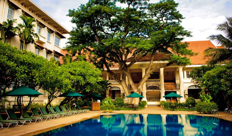Raffles Hotel Le Royal Cambodia exterior pool loungers trees hotel building