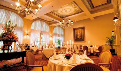 Raffles Hotel Le Royal Cambodia restaurant indoor dining room traditional decor chandeliers floral arrangement