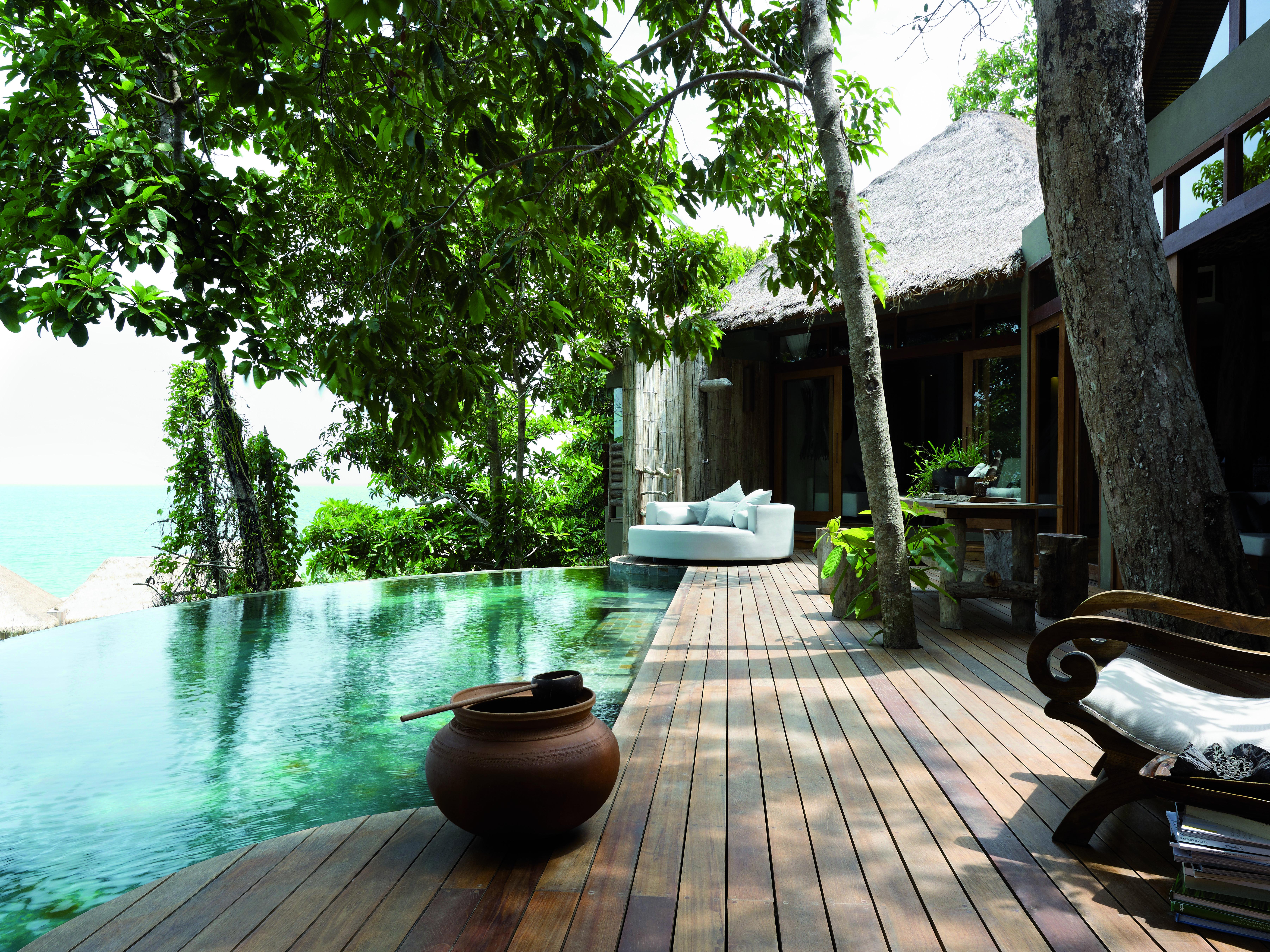View of the exterior of a two bedroom villa at the Song Saa Private Island hotel with an infinity pool, wooden decking and sun loungers