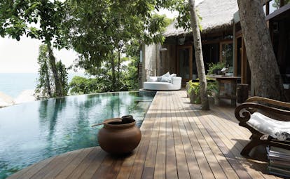 View of the exterior of a two bedroom villa at the Song Saa Private Island hotel with an infinity pool, wooden decking and sun loungers