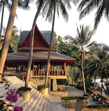 Exterior of hotel with large palm trees and sunloungers shown around the pool