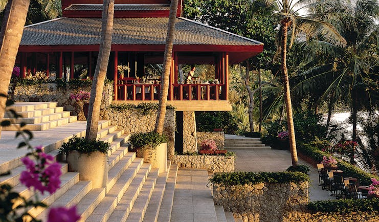 Exterior of hotel with large palm trees and sunloungers shown around the pool